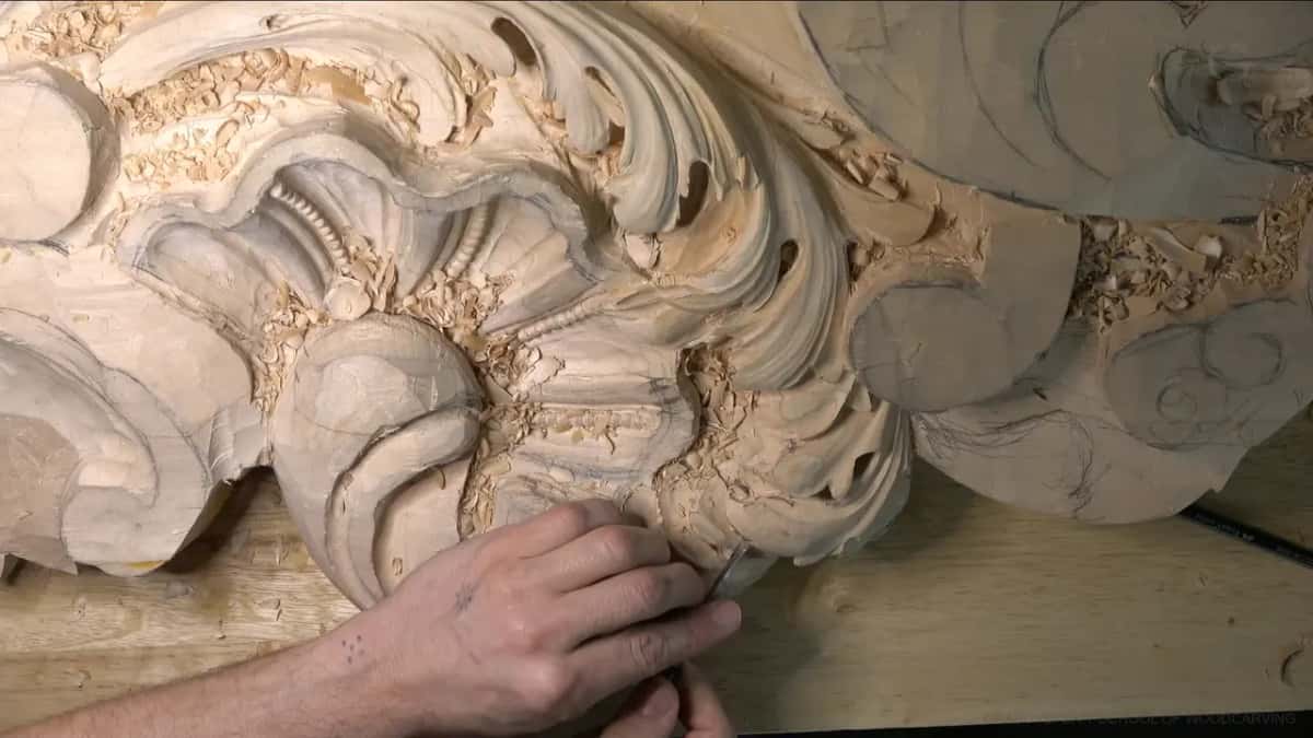 One hand works a slim gouge along the lower lobe edge.