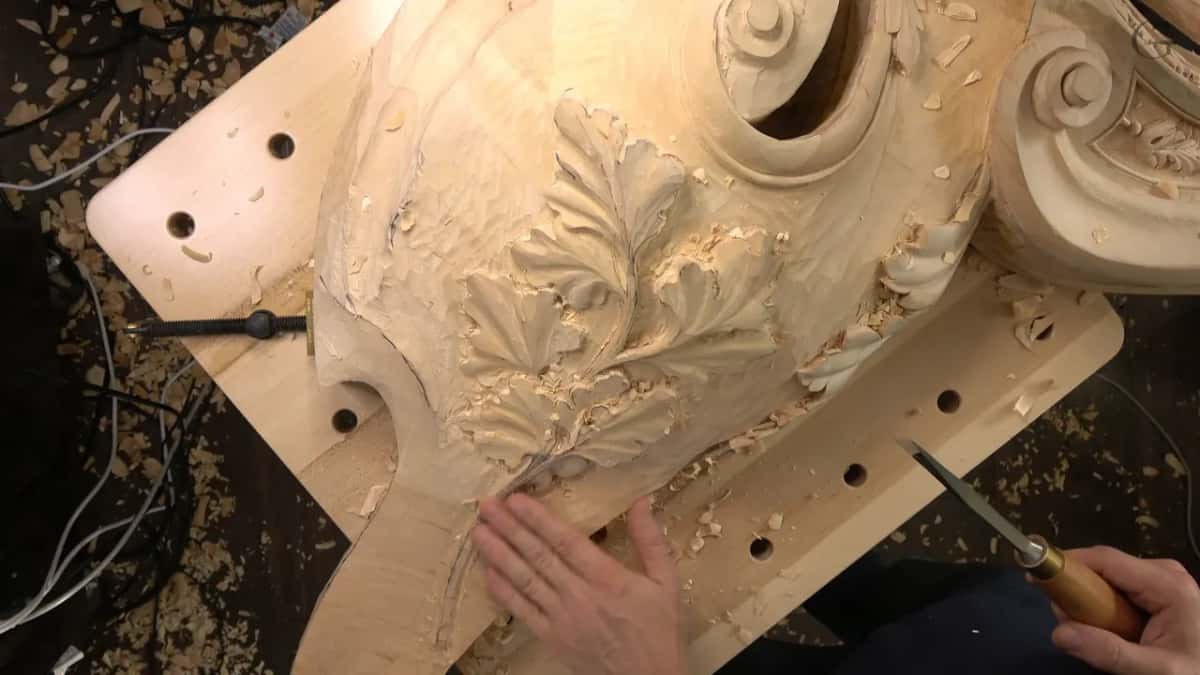 Left hand flat on the board by the stem, a narrow blade with a wood handle in the right