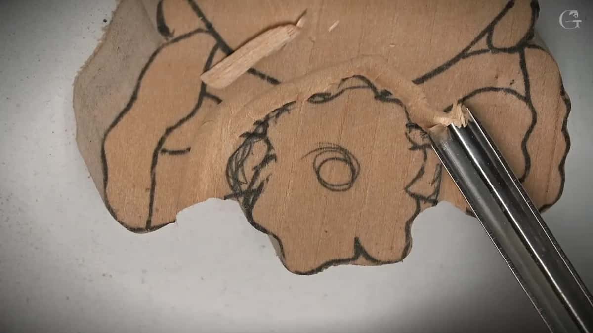 Chip curling up where the gouge meets a black line, a ring already carved round the middle