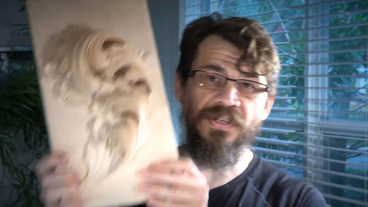 Part carved acanthus leaf on a pale board, held up to the camera