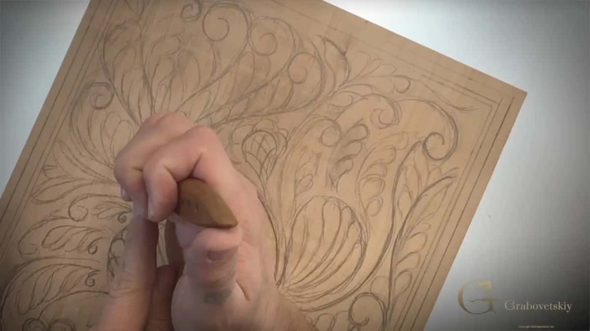Blade point pressed down into a pencil line near the middle of the drawing, a fist wrapped round the handle