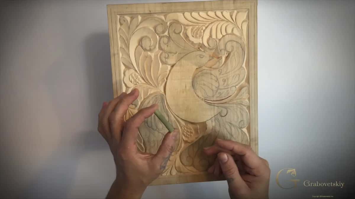 Short green stem of Dutch reed held against the carved panel
