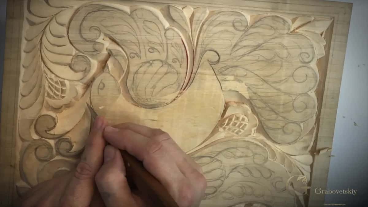Close on the beak, two hands guide the blade along the outline