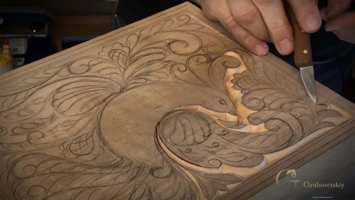 Knife upright at the beak, with the carved outline curving past the flower.