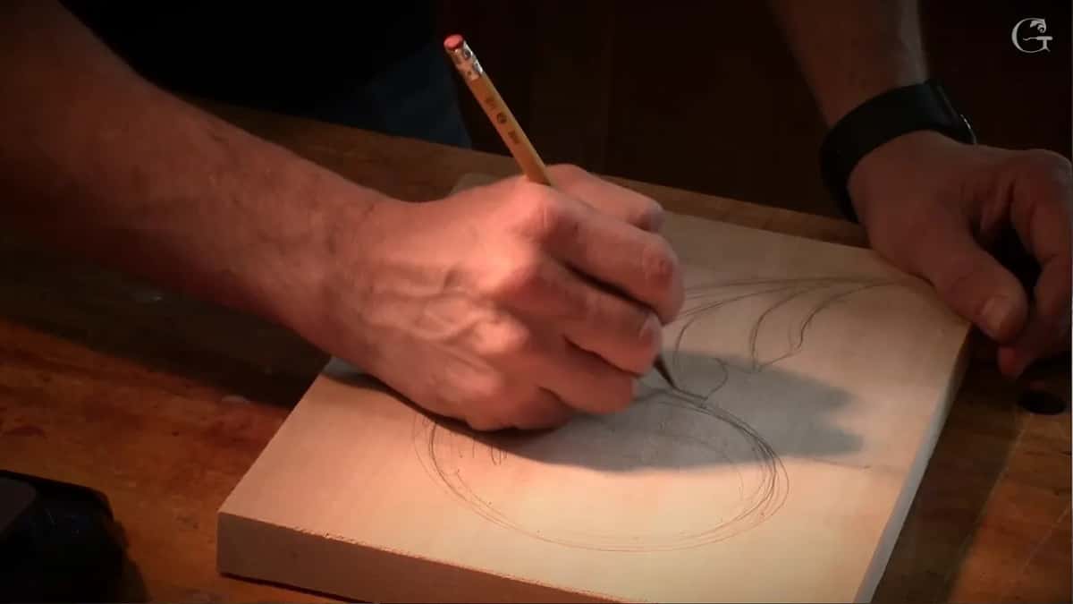 Pencil adding leaf lobes along the top of the swirl while the other hand holds the board
