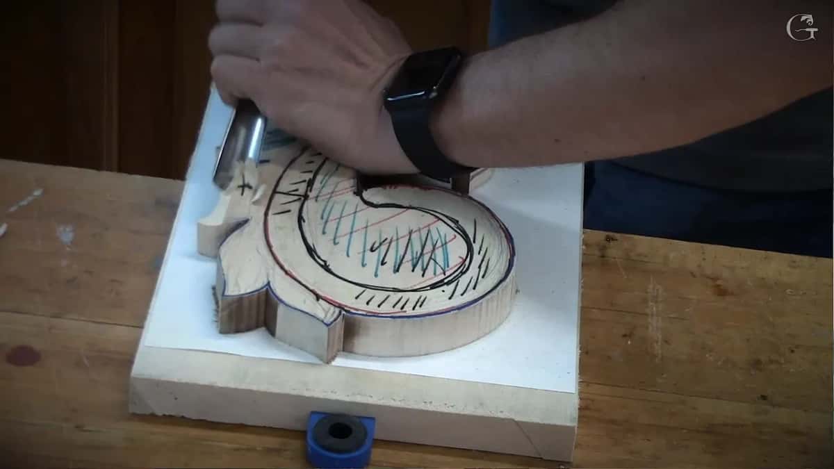 Carving on, the hand low over the work