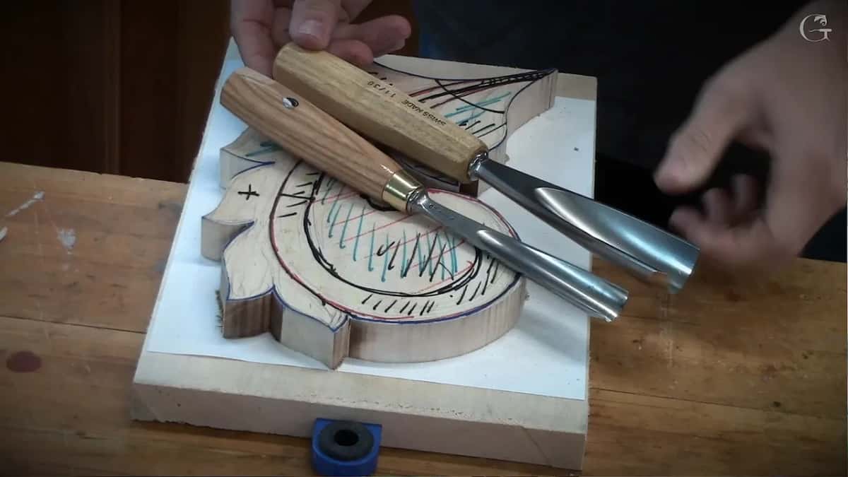 Two gouges lying side by side on the marked blank, handles to the upper left