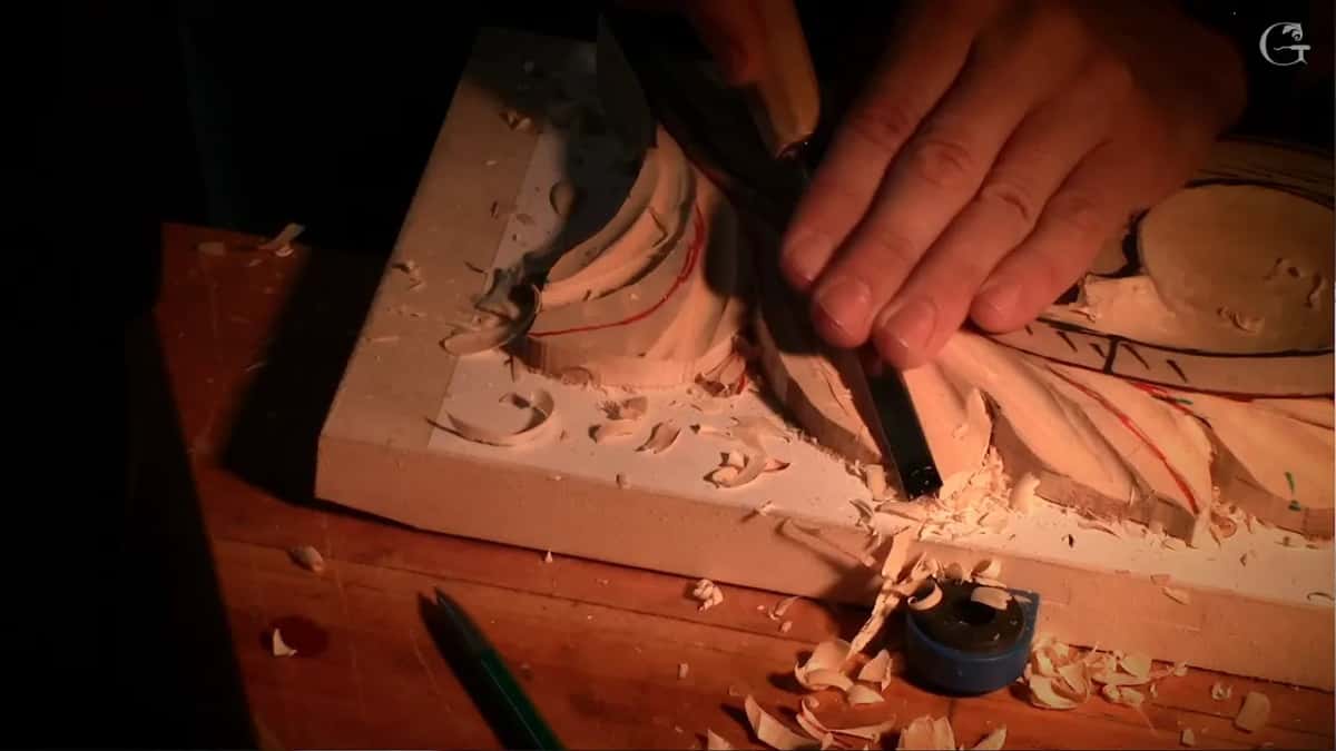 Fresh chips pile up at the edge of the board where a gouge works the hollow