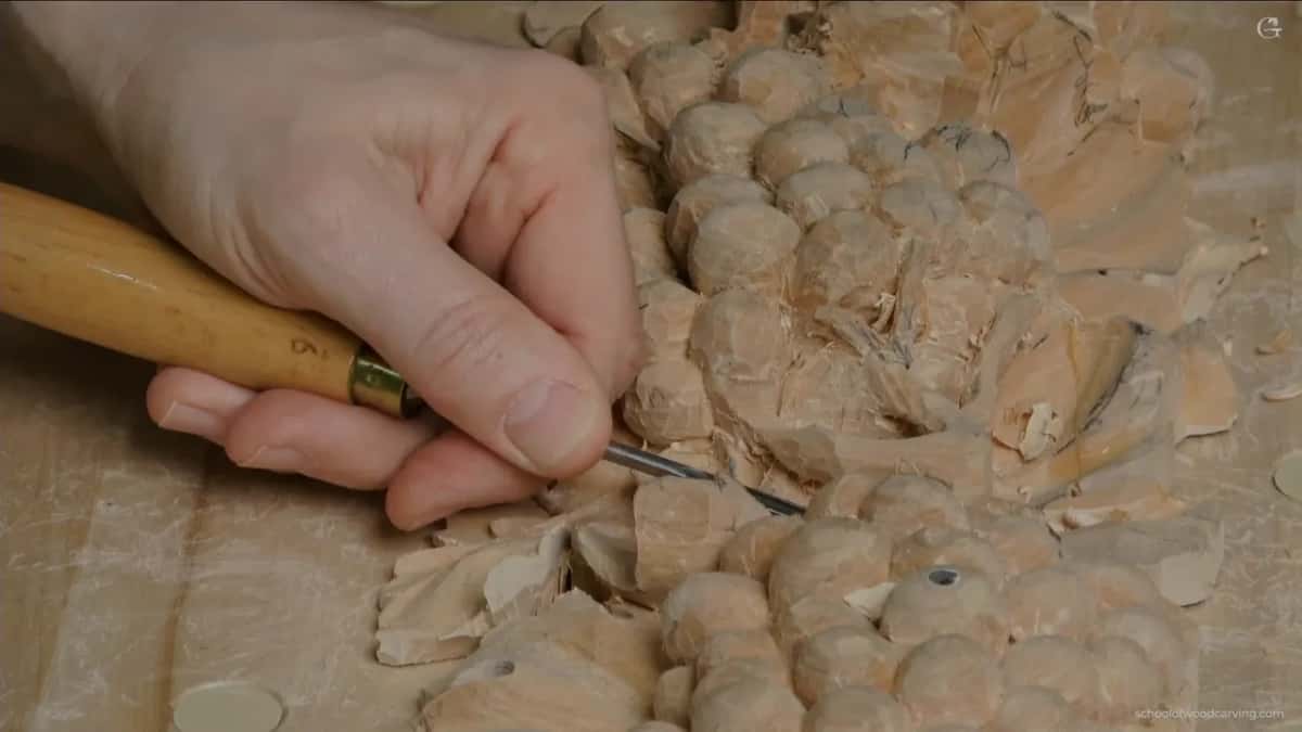 Light wood handle and brass ferrule in one hand, the tip working down among the round grapes
