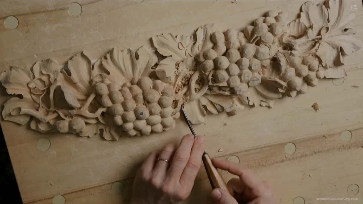Both hands on one tool, working the middle of the panel from above, leaves on either side