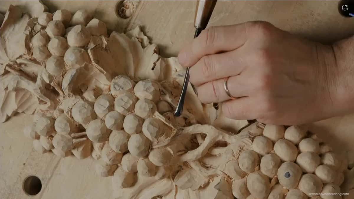 Fingers wrapped close around a small tool among the grapes