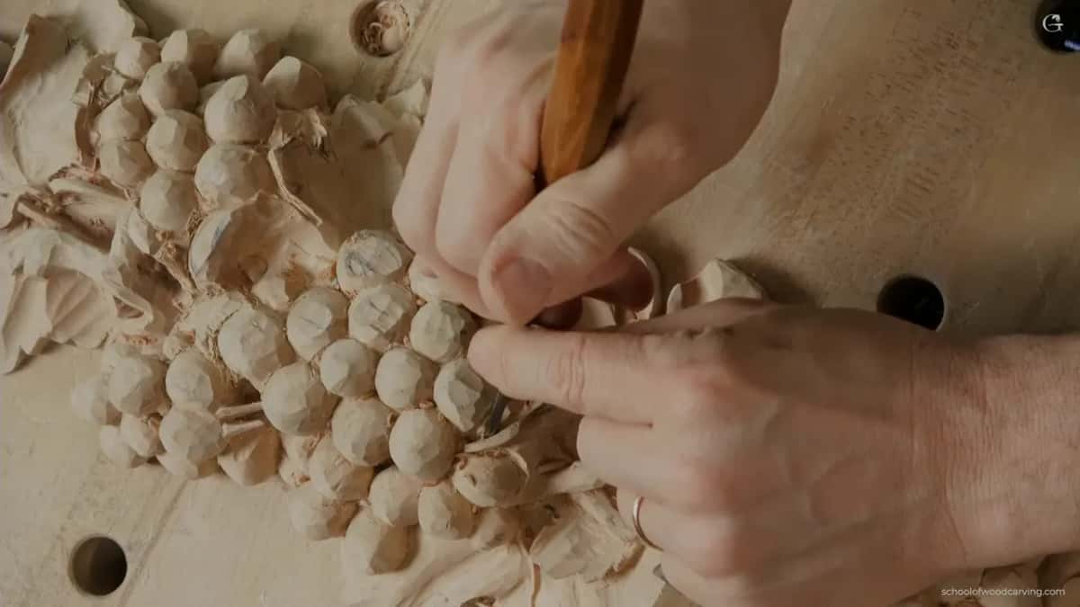 Left fingers guide the blade while the right hand holds the handle, chips piling up around the bunch