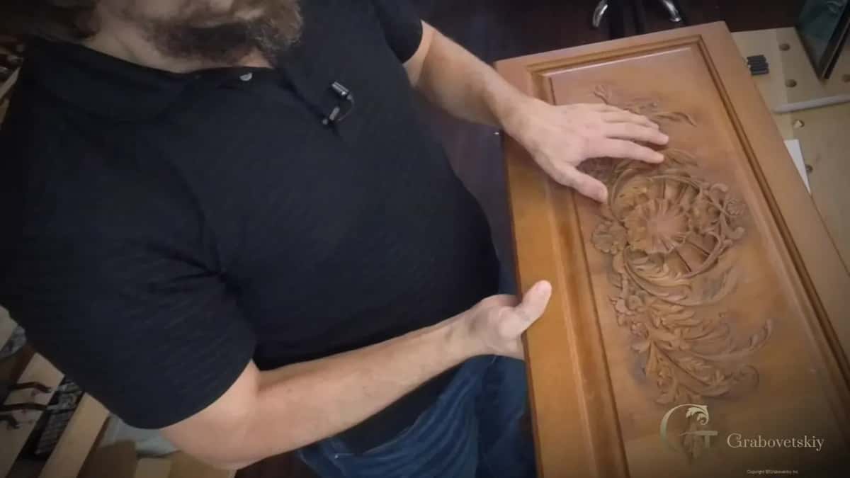 Hands spread on a tall carved furniture panel, a large flower among acanthus leaves at its center