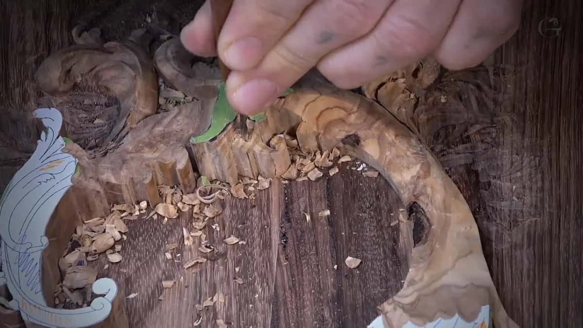 Fingertips pushing a small tool down by the green patch