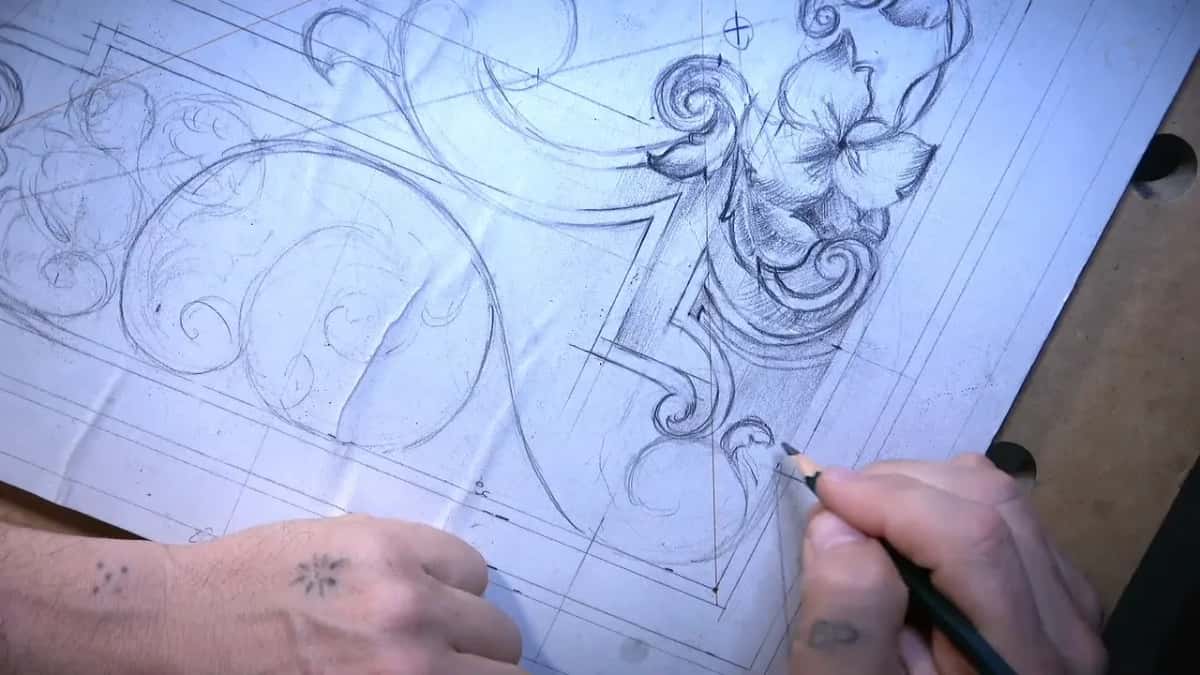Two hands low on the sheet, the right drawing a scroll by the shaded strip