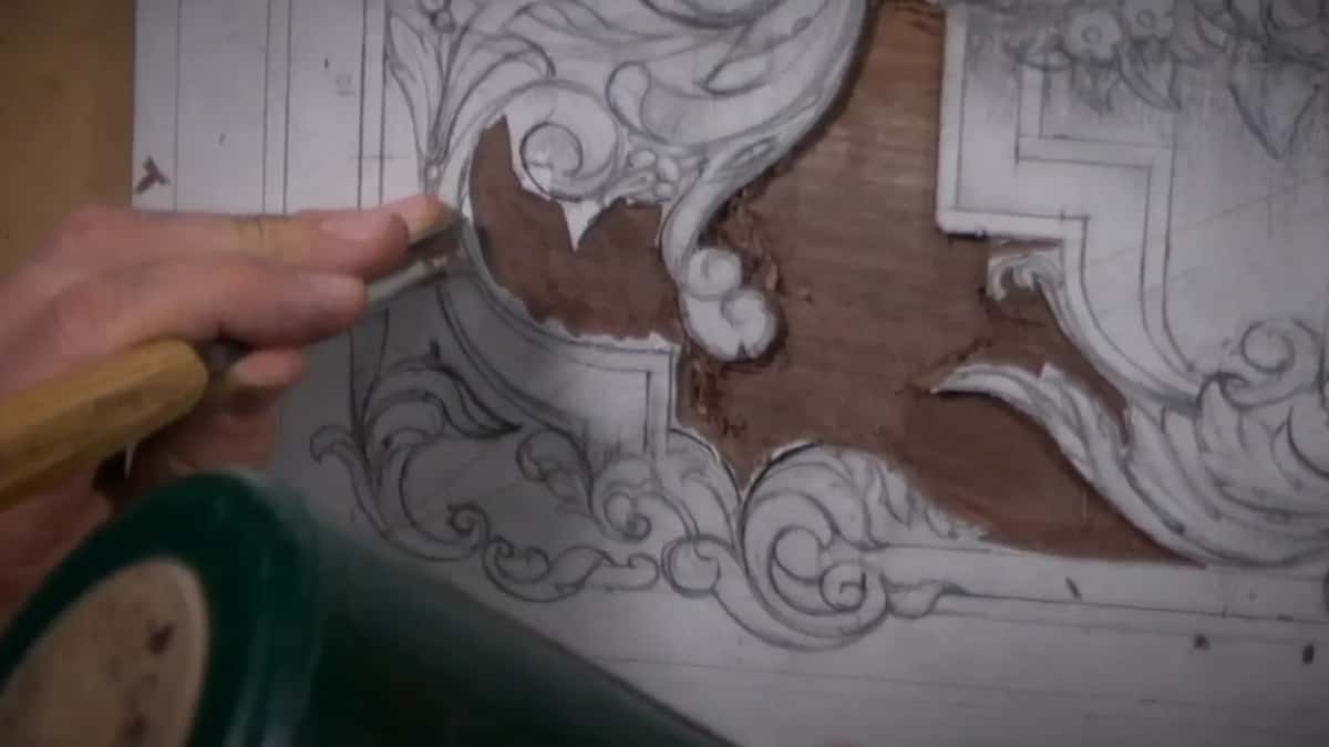 Green mallet driving a gouge in beside the drawn edge, wood chips already scattered around it