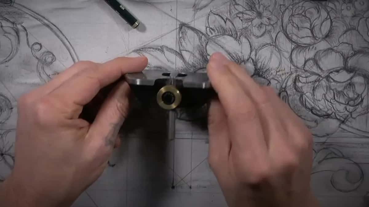 Both hands lift the small router plane above the drawing