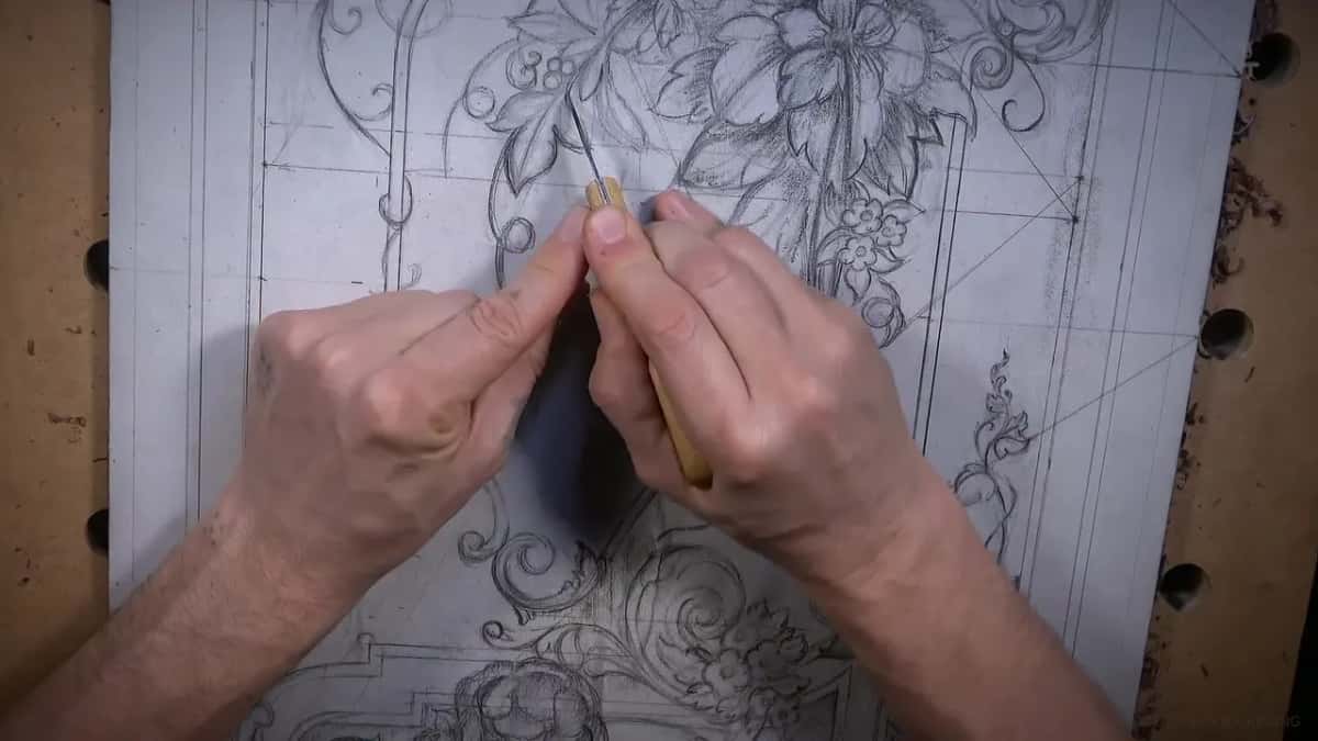 Seen from above, a knife tip in the pencil line beside a scroll, two hands on its handle