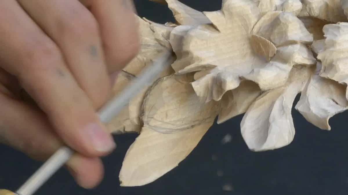 A slim tool with a pale handle follows the pencil outline of the leaf