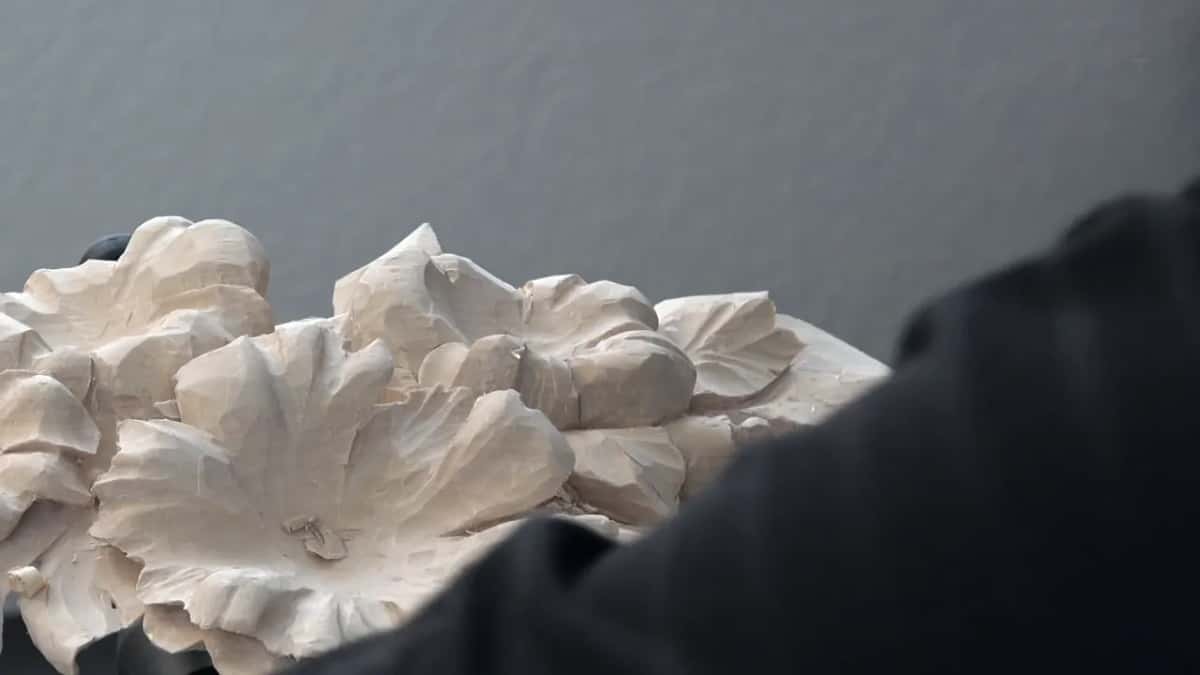 Carved flowers seen side on, with a dark sleeve reaching in from the right