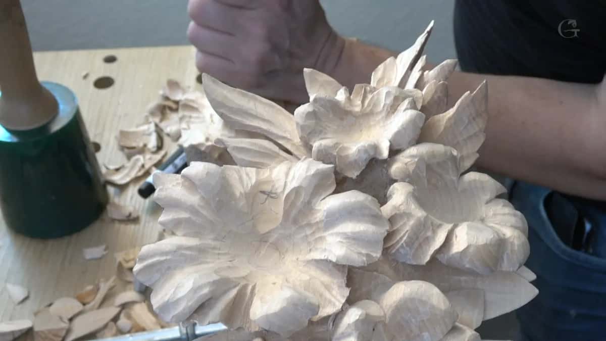 Carved flowers fill the front of the frame, his fist raised behind them and a green mallet on the left