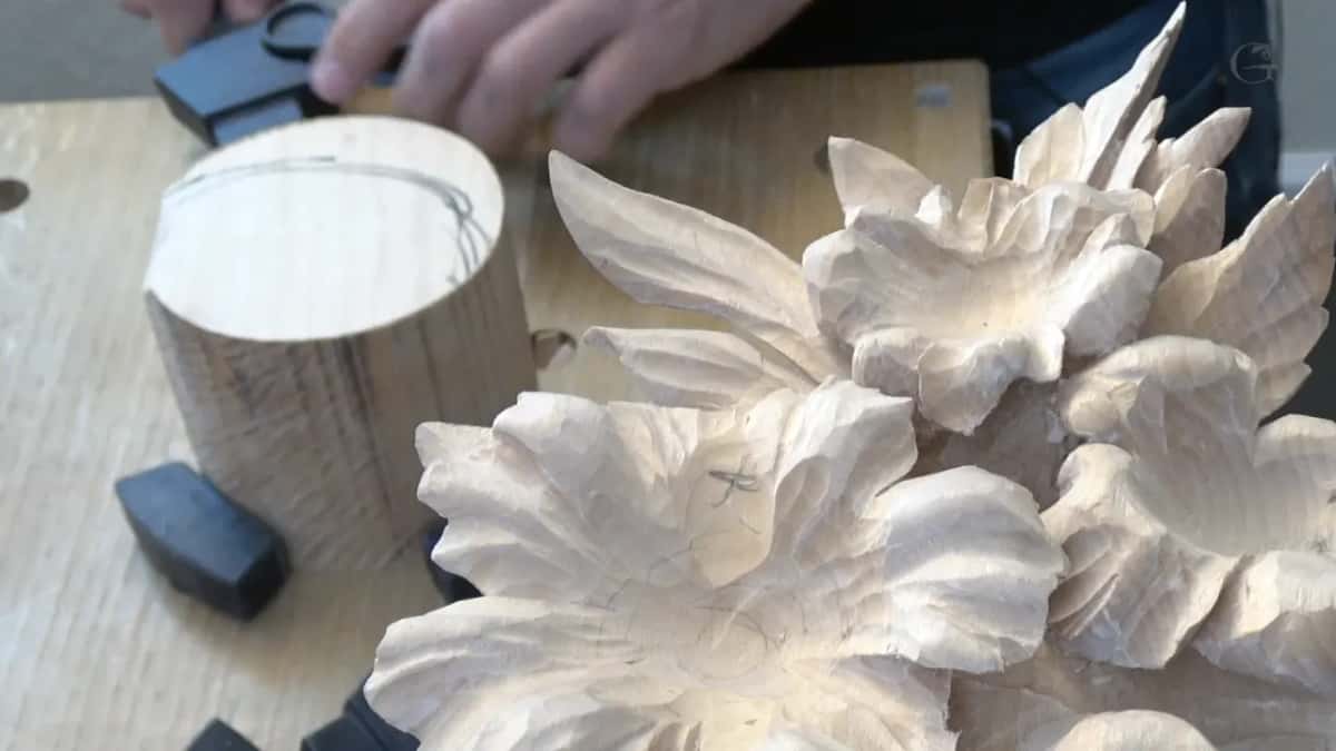 A round block stands on the bench beside the carved flowers, two black stops at its foot