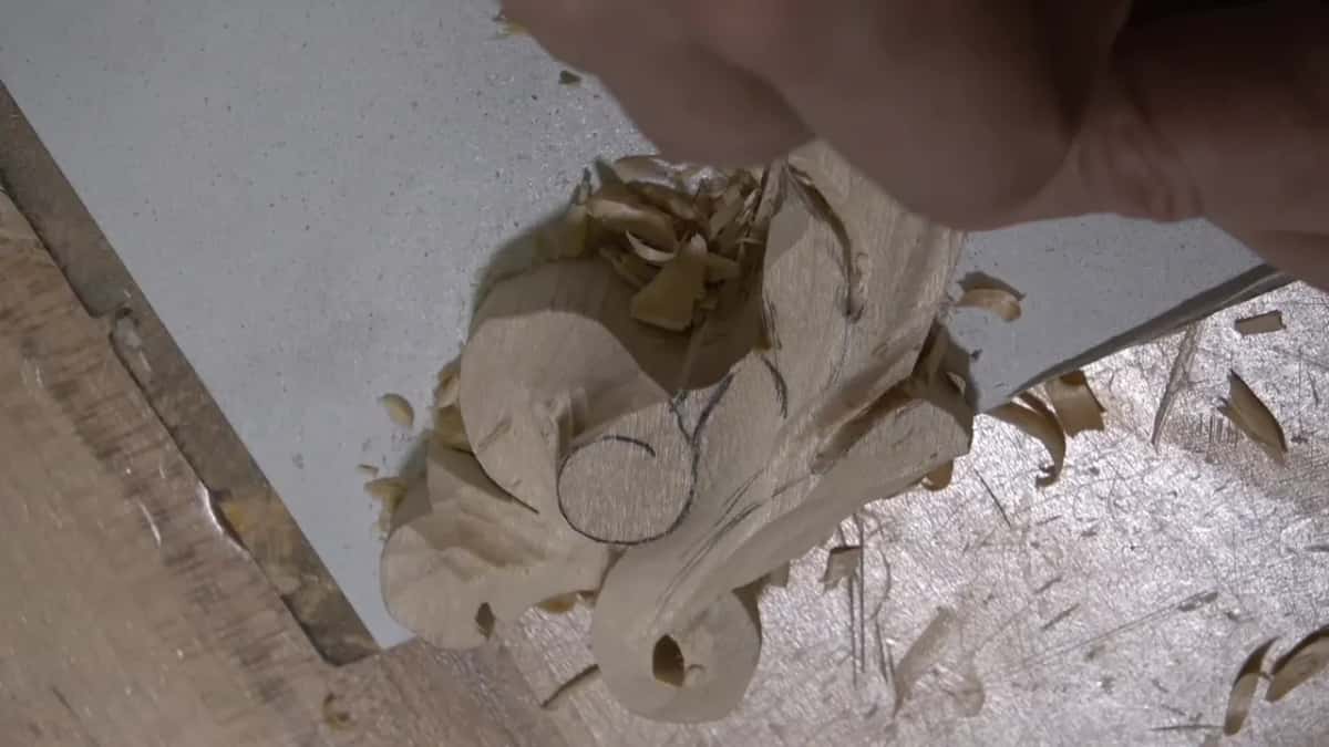 Scroll from above, with fingers over the leaf and a few shavings lying below it