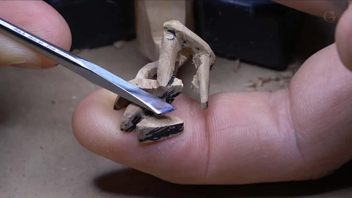 Narrow blade slipping in between two legs, with the cluster propped up on one fingertip.