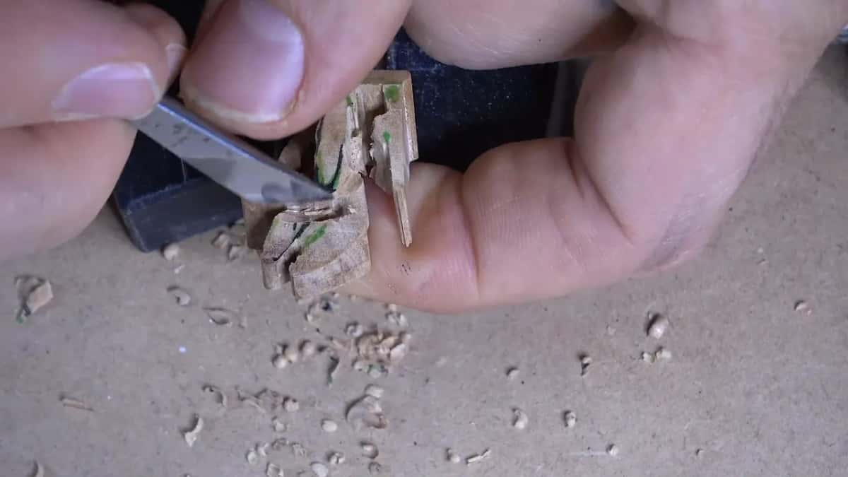 A knife slices into the cluster while one fingertip presses up from behind it.