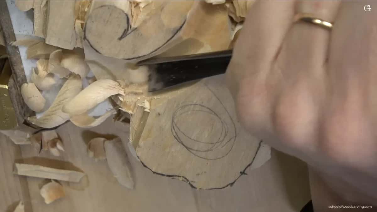 Shavings fly off the edge of the blank as the blade slices along beside the drawn line.