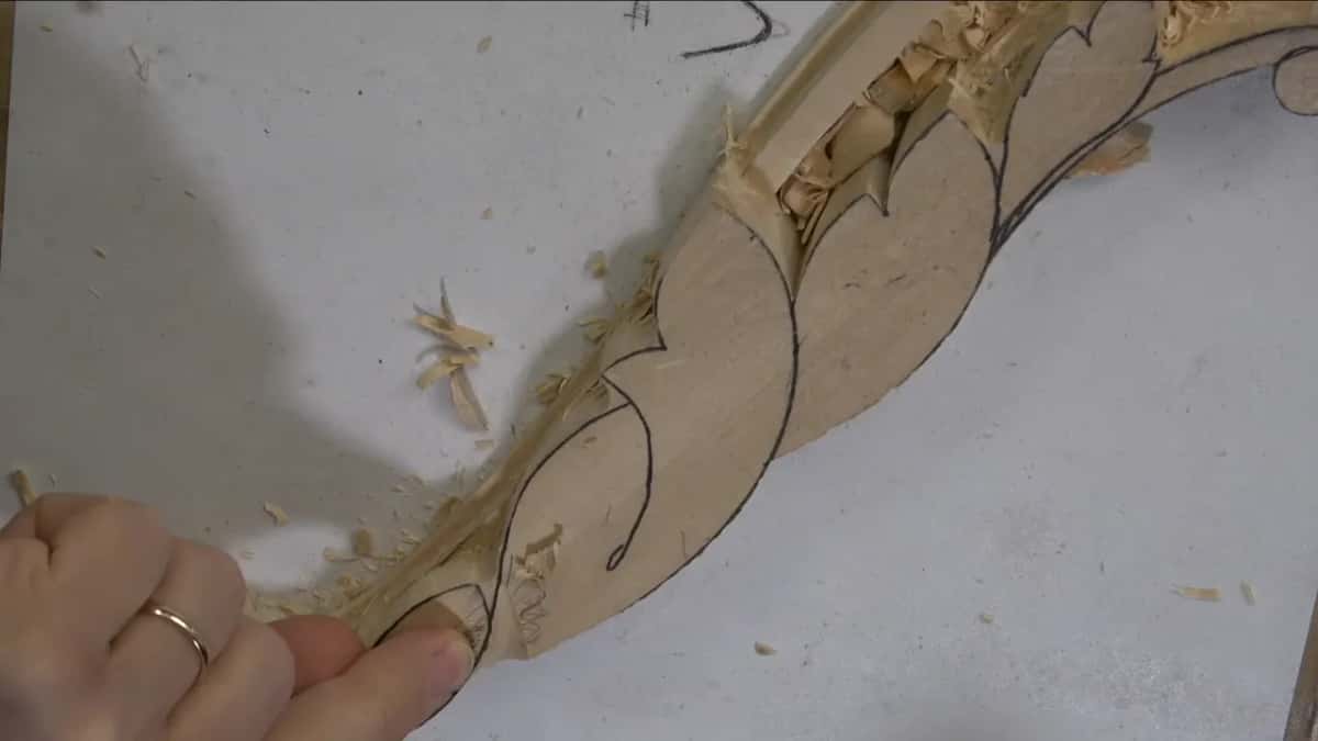 Fingertips beside a fresh channel, with shavings still lying in it.