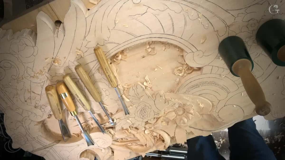 Overhead view of the panel with five gouges in a row and two green mallets resting near the flower