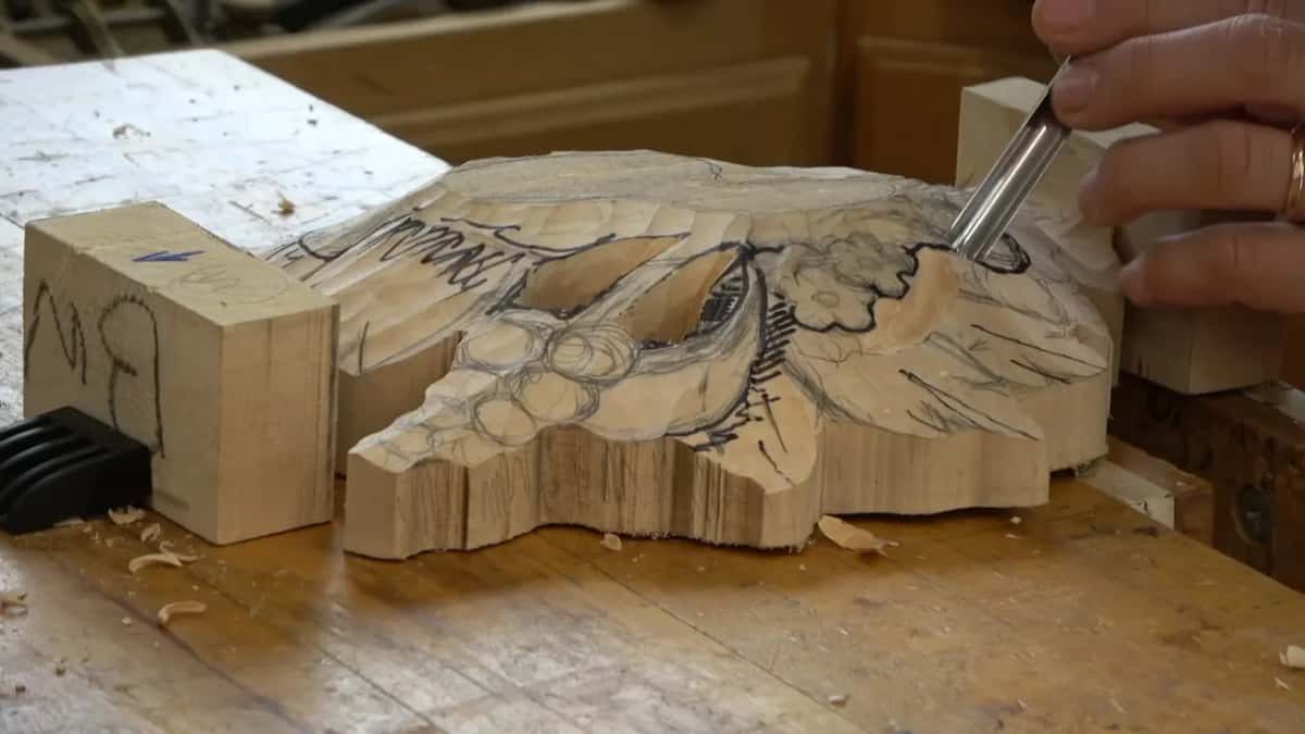 Gouge cutting the channel around a drawn flower, pierced opening already cut through the panel beside it