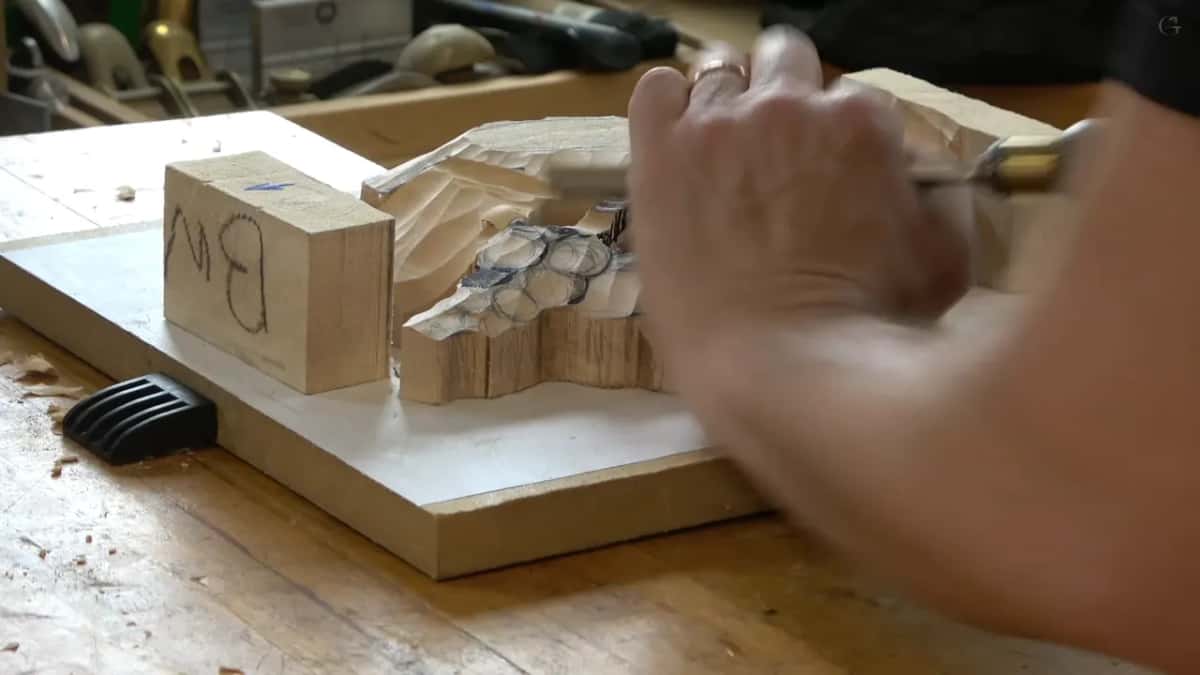 Two hands steer a brass ferruled gouge into the inked circles