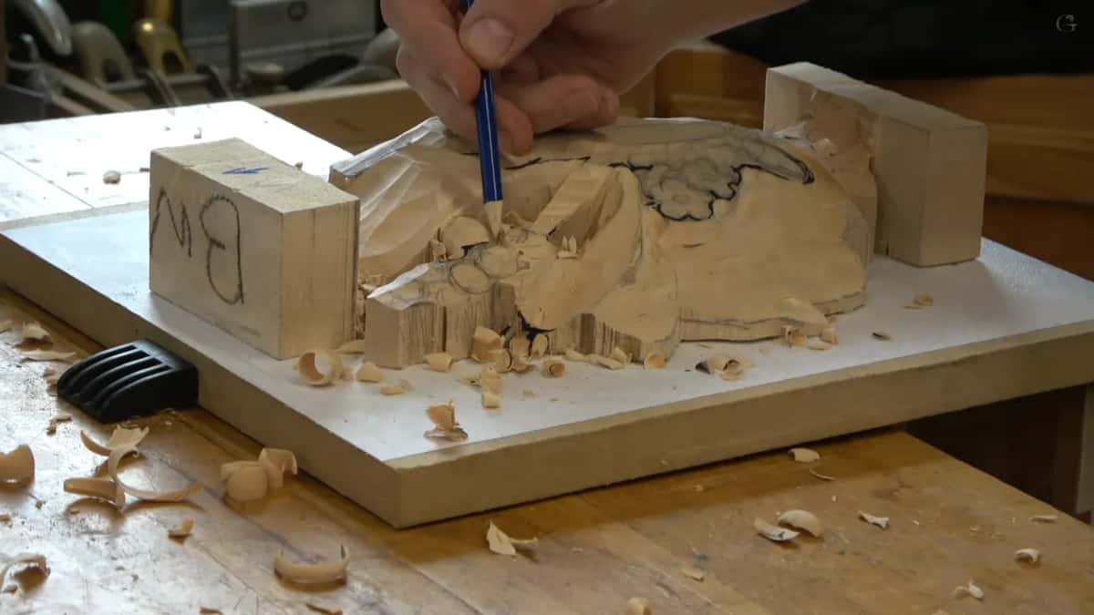 Pencil back on the cluster while shavings lie around the blocks that hold the carving