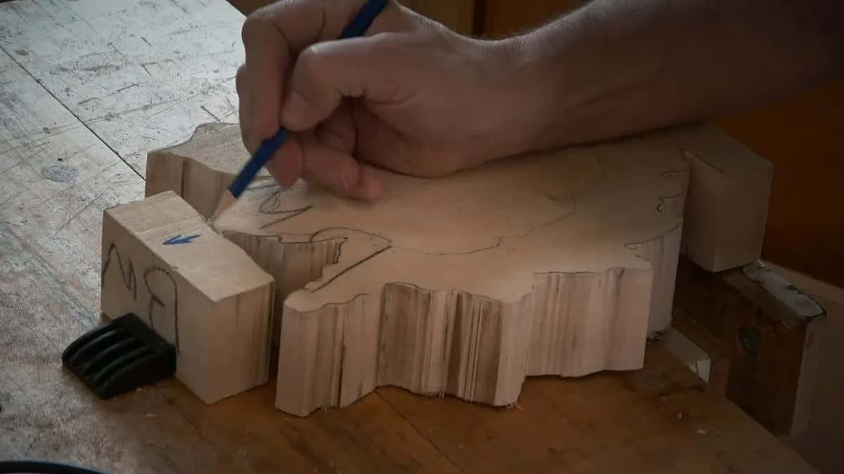 Pencil redrawing a line across the blank, leg tab marked with a blue arrow