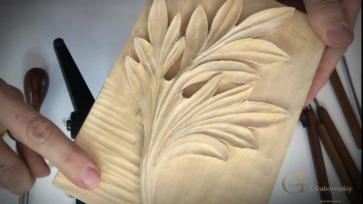 Both hands hold the finished panel up, and slicing ridges still show across the ground on the left.