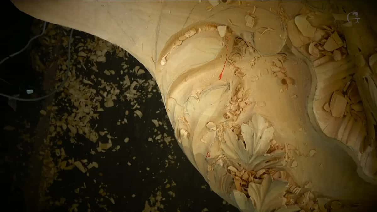 Straight down into the deep hollow, a small red arrow on its wall, shavings heaped around carved leaves.