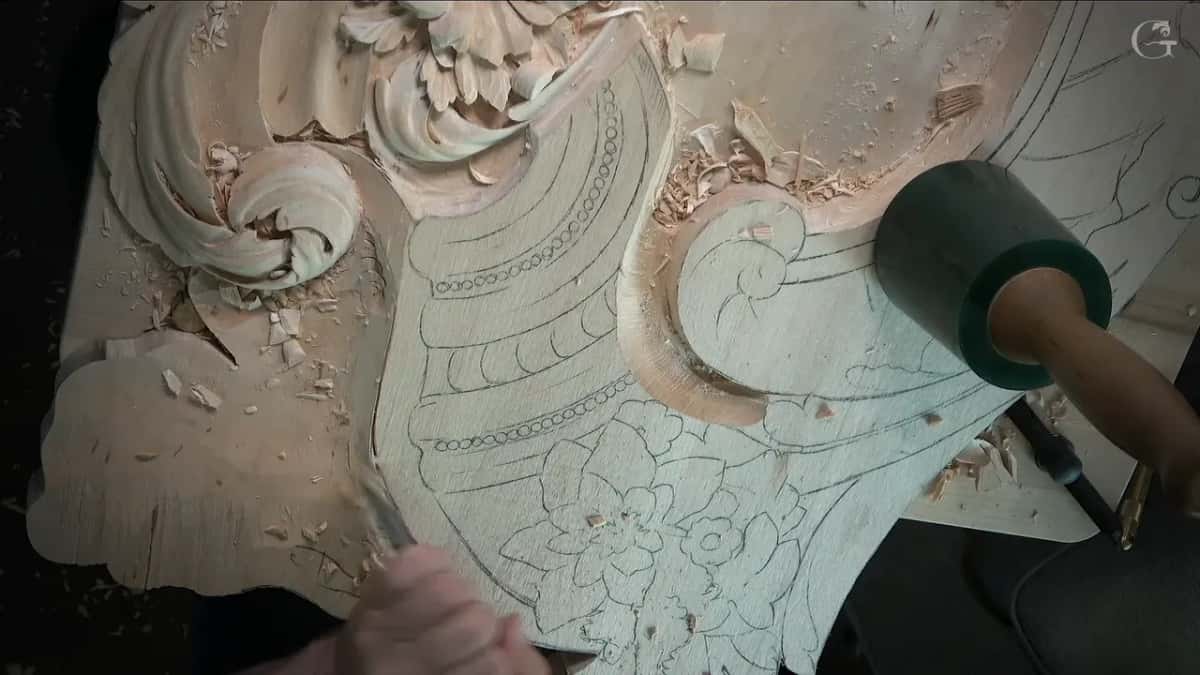 Mallet at the right while the other hand holds a tool down on the pencil lines