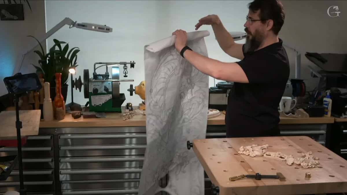 A long paper drawing held up in both hands by the bench