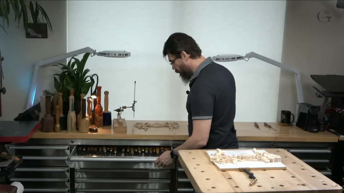One studio drawer pulled open, rows of tool handles inside, the panel waiting on the bench in front
