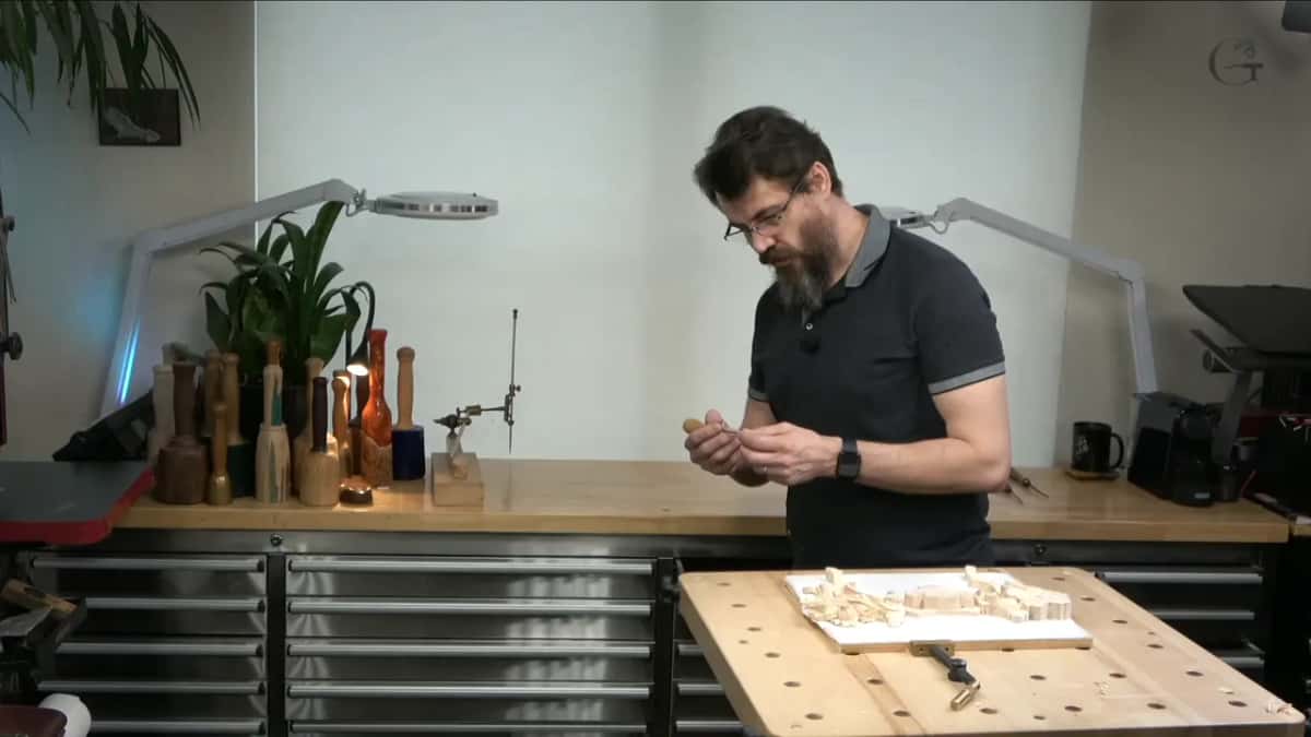 Standing at the bench, he looks down at a small tool in his hands