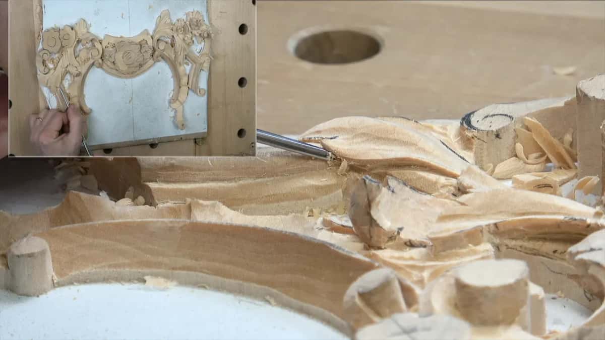 Low view along the molding as a thin gouge goes in behind round stubs, the panel inset at left