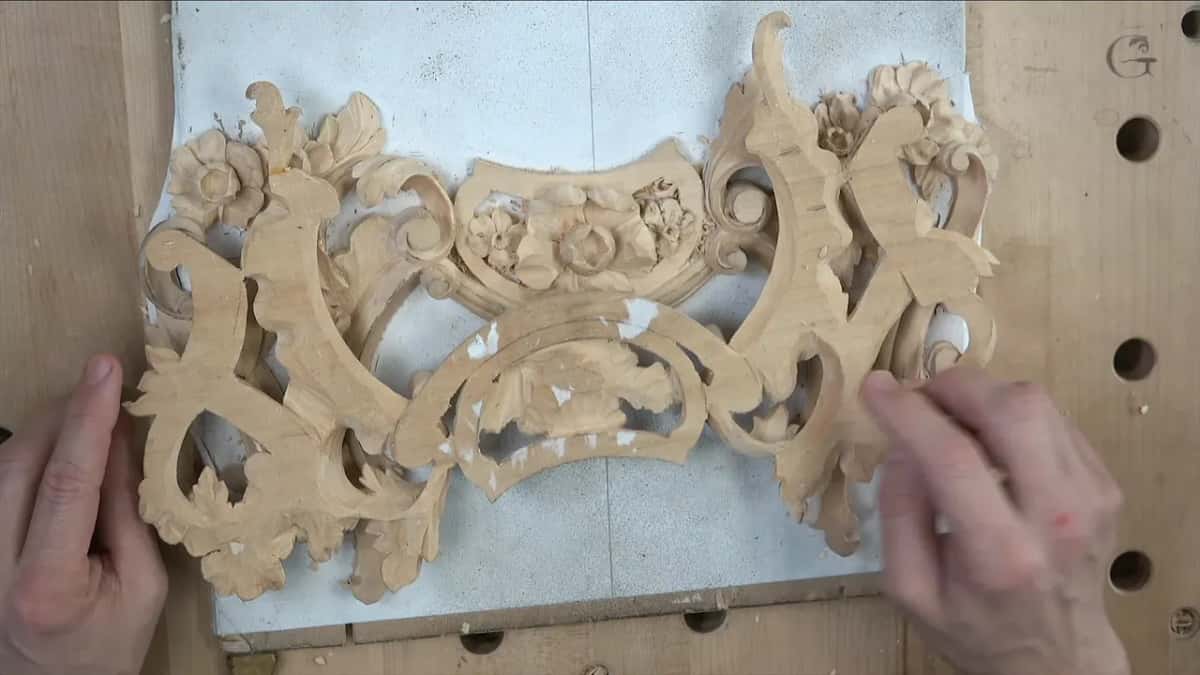Both hands lift one carved piece above the other on the white board