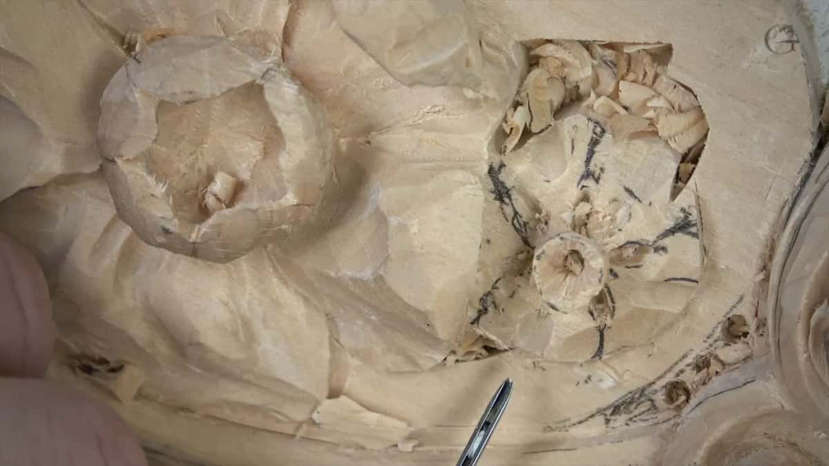 Pencil lines across the carved petals around the center, with a tool tip showing at the lower edge