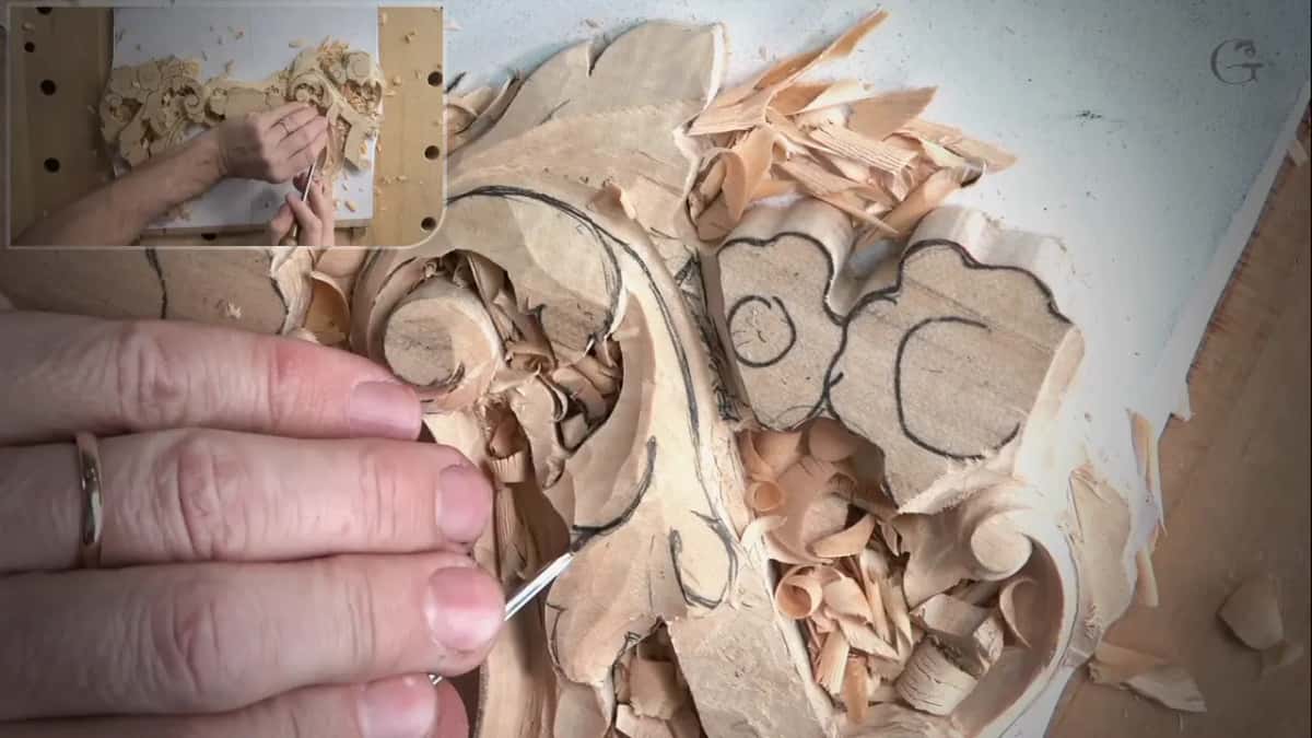 Fingers guide a very thin tool along an inked line near the drawn flower
