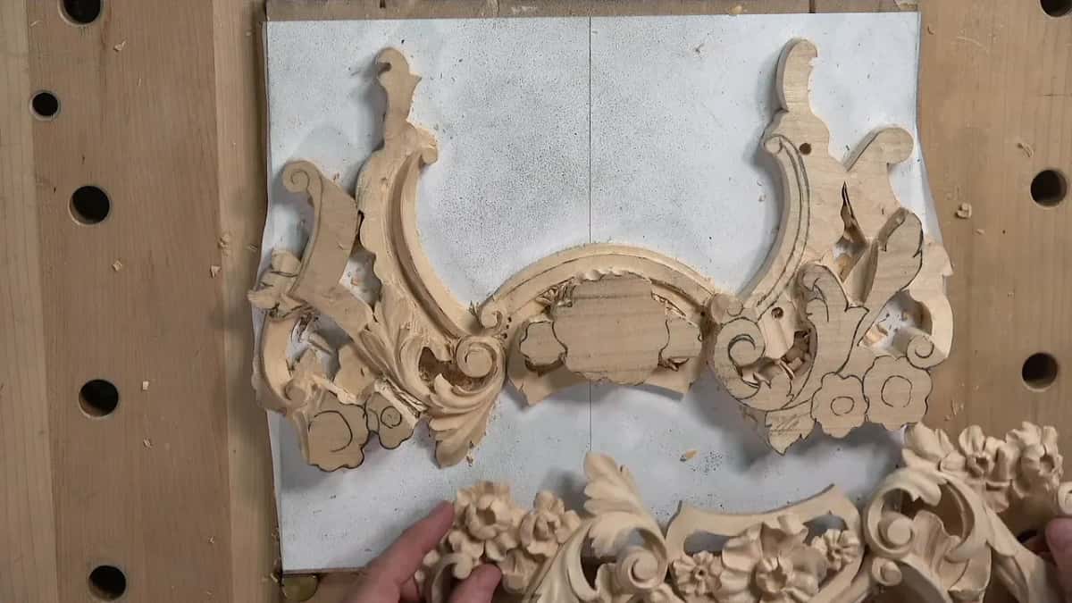 Finished first piece held up below the new panel, upside down, with its carved flowers facing the camera