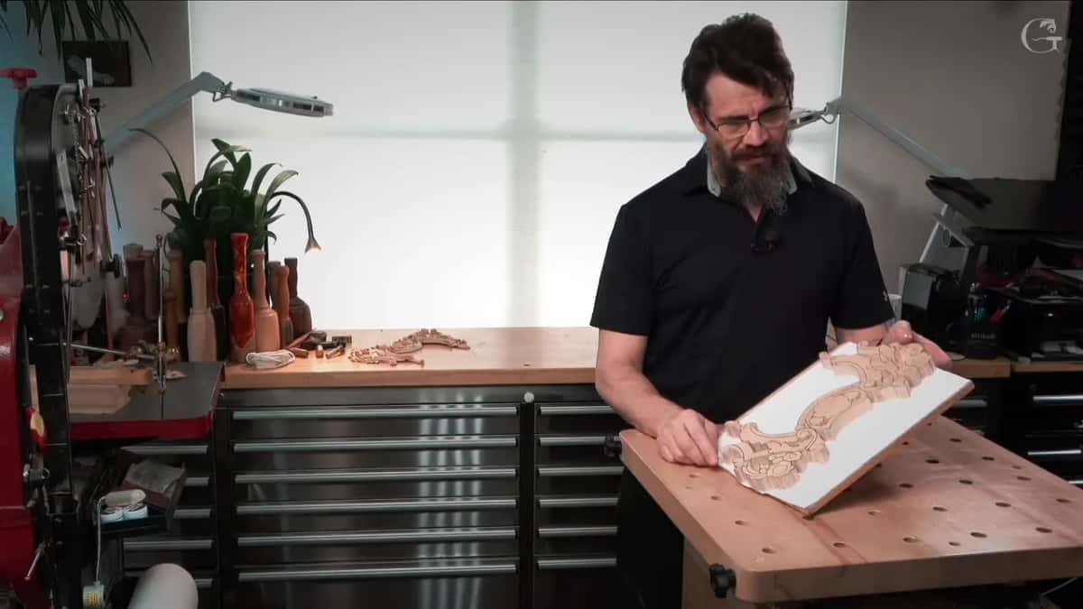 Standing at the bench holding the piece