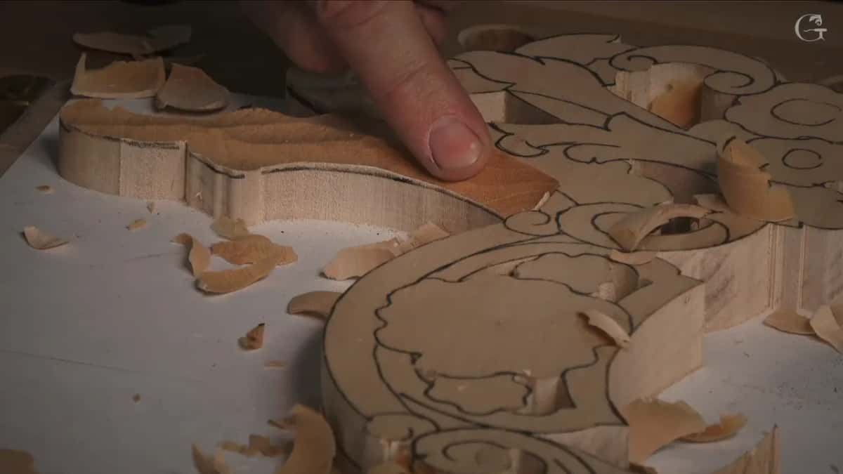 A hand steadying the blank while the outline is worked