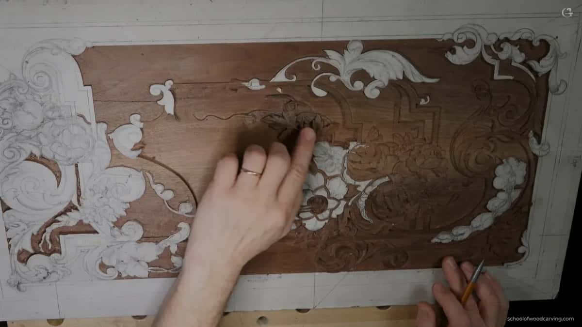 The walnut panel from above, one hand resting on it and the other holding an orange pencil.